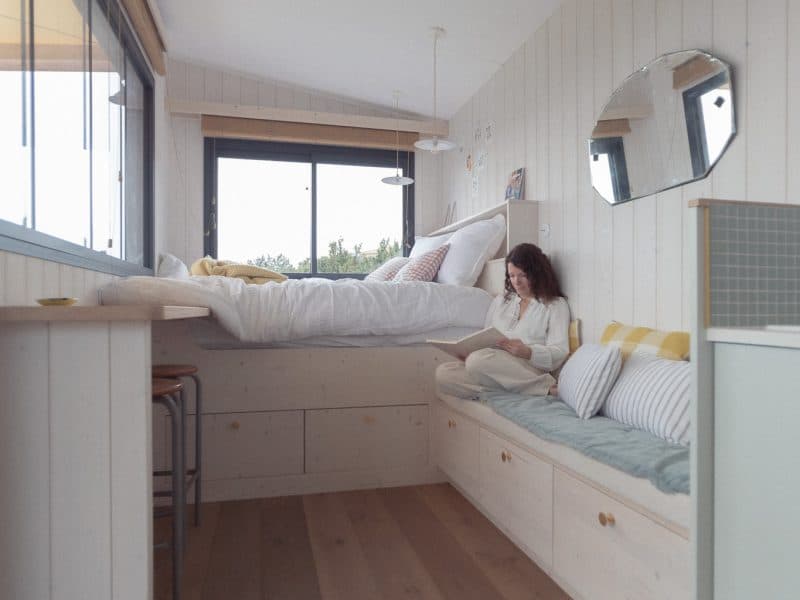 Chalet moderne avec lit confortable et vue panoramique, ambiance chaleureuse et lumineuse.