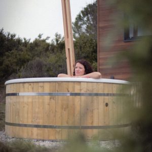 Cabane en bois avec baignoire en bois, offrant une vue sur la nature environnante.