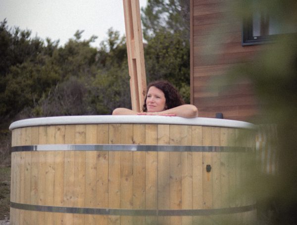 Cabane en bois avec baignoire en bois, offrant une vue sur la nature environnante.