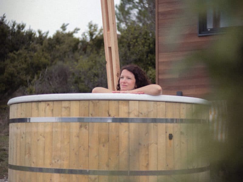 Cabane en bois avec baignoire en bois, offrant une vue sur la nature environnante.