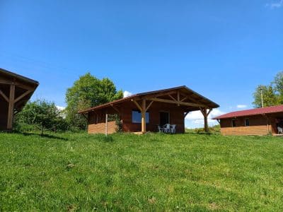 Chalet en bois à Auvergne, avec terrasse et vue sur la verdure environnante.