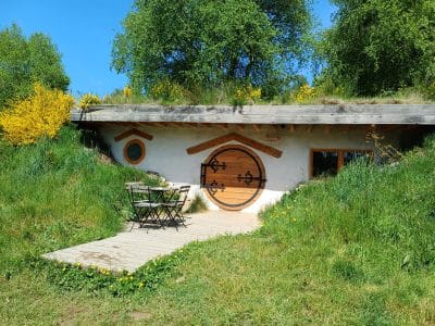 Hébergement insolite en Auvergne : maison troglodyte avec porte ronde et terrasse en bois.