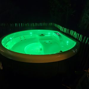Hébergement insolite en Hauts-de-France avec jacuzzi lumineux entouré de verdure.