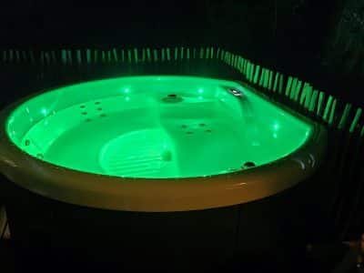 Hébergement insolite en Hauts-de-France avec jacuzzi lumineux entouré de verdure.