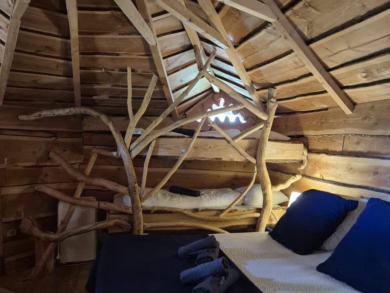 Cabane en bois avec lit douillet et décor naturel en Auvergne-Rhône-Alpes.
