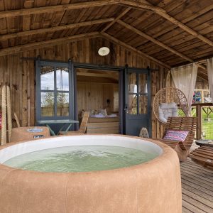 Cabane en bois avec jacuzzi, offrant une vue sur la nature verdoyante.