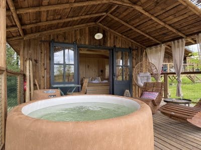 Cabane en bois avec jacuzzi, offrant une vue sur la nature verdoyante.
