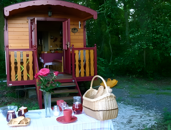Roulotte colorée au milieu de la nature, avec une table dressée et des viennoiseries.