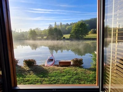 Cabane sur leau en Aquitaine, vue sur un lac embrumé et un petit bateau.