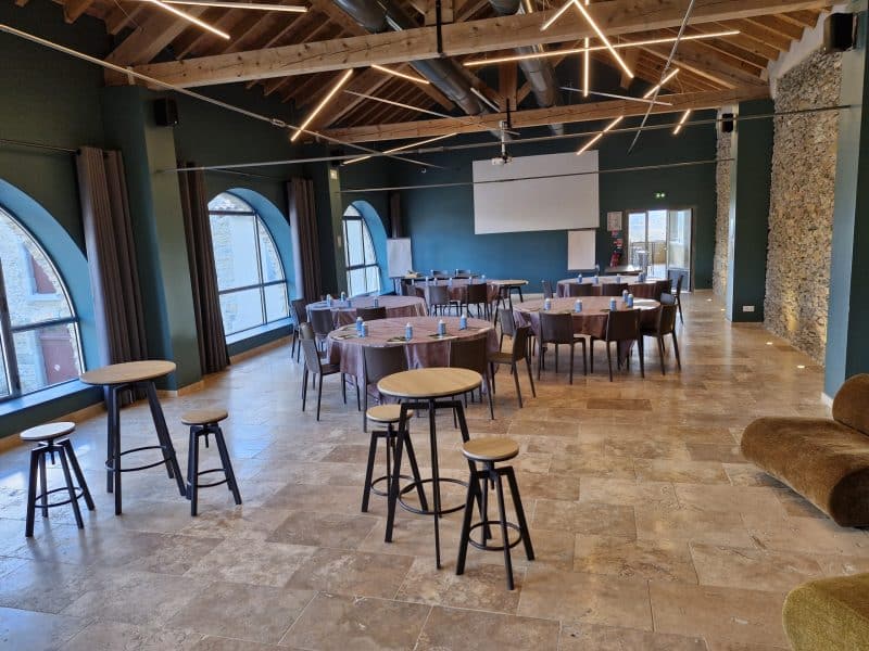 Salle de séminaire moderne avec tables rondes et éclairage design.