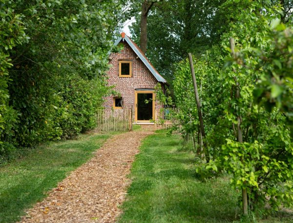 Charmante maison en briques, entourée de verdure et dun chemin en gravier.