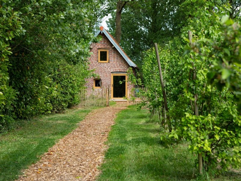 Charmante maison en briques, entourée de verdure et dun chemin en gravier.