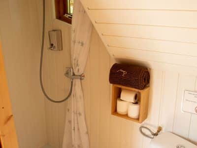 Salle de bain dun hébergement insolite en bois, avec douche et toilettes modernes.