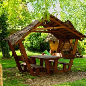 Hébergement insolite en Hauts-de-France : cabane en bois avec toit de chaume et table.