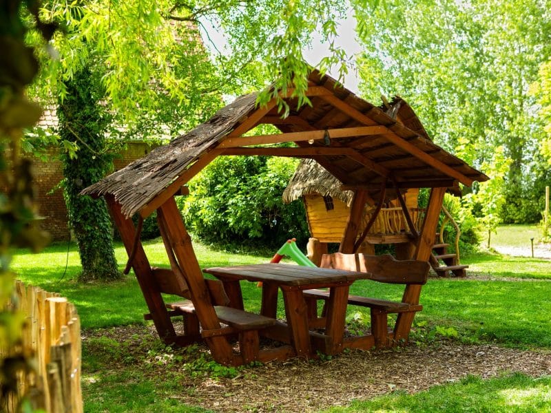 Abri en bois avec table et bancs, idéal pour un séjour en pleine nature.