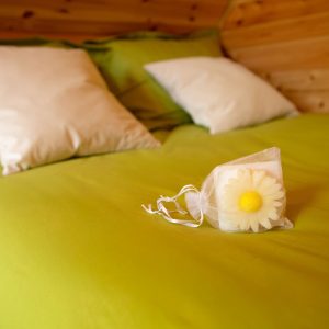 Chalet en bois avec lit douillet et coussins, décoré dune fleur en savon.