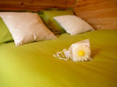 Chalet en bois avec lit douillet et coussins, décoré dune fleur en savon.