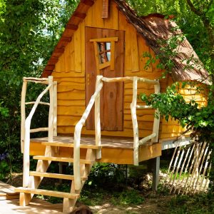 Cabane en bois dans les Hauts-de-France, avec un chien reposant devant.