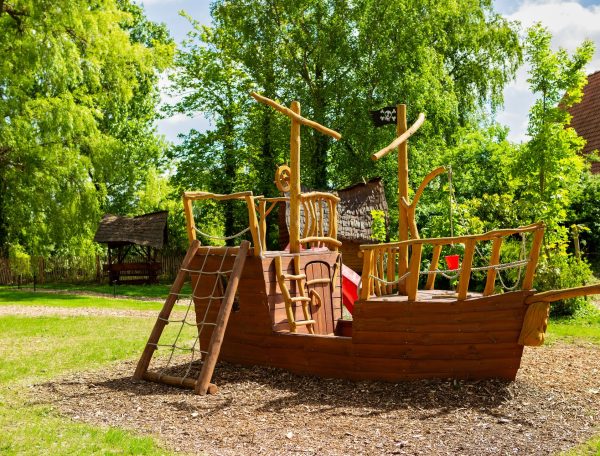 Aire de jeux en bois en forme de bateau pirate, idéale pour les familles.