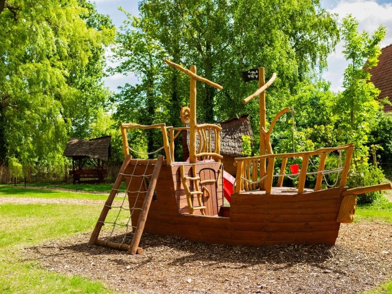 Aire de jeux en bois en forme de bateau pirate, idéale pour les familles.