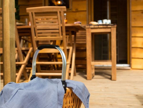 Charmante cabane en bois avec un panier pique-nique sur la terrasse ensoleillée.