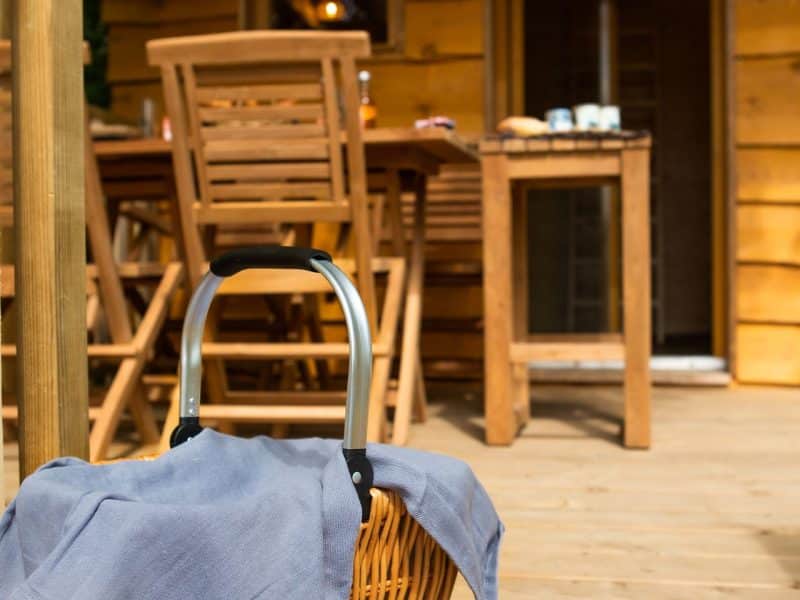 Charmante cabane en bois avec un panier pique-nique sur la terrasse ensoleillée.