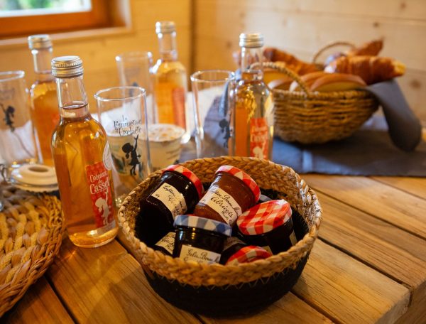 Chalet en bois avec confitures artisanales et boissons locales sur une table en bois.