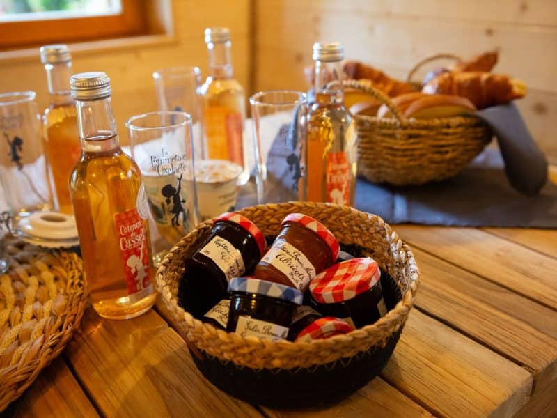Chalet en bois avec confitures artisanales et boissons locales sur une table en bois.