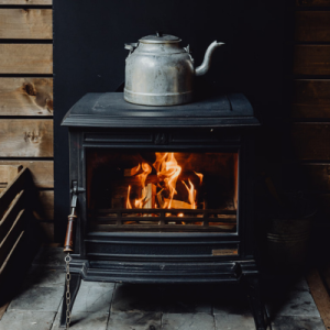 Chalet en bois avec un poêle à bois et une bouilloire vintage sur le dessus.