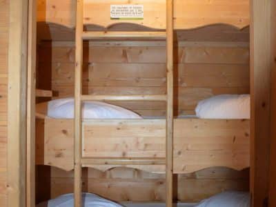 Cabane en bois avec lits superposés, ambiance chaleureuse et naturelle.