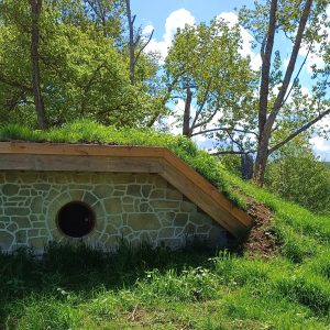 Hébergement insolite en Auvergne : un gîte troglodyte entouré de verdure au bord de leau.