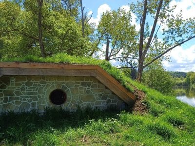 Hébergement insolite en Auvergne : un gîte troglodyte entouré de verdure au bord de leau.