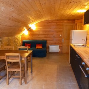 Hébergement insolite en Auvergne : chalet en bois avec cuisine ouverte et coin salon.