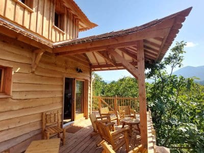 Cabane en bois avec terrasse ensoleillée et vue sur les montagnes en Auvergne-Rhône-Alpes.
