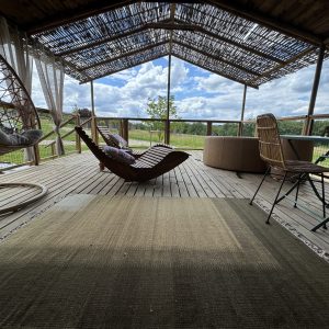 Hébergement insolite en cabane avec terrasse en bois et fauteuils suspendus.