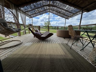 Hébergement insolite en cabane avec terrasse en bois et fauteuils suspendus.