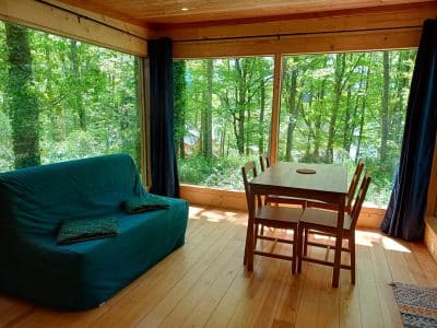Cabane en bois avec grandes fenêtres donnant sur la forêt verdoyante dAuvergne.