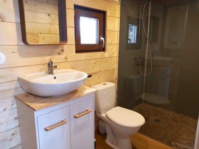 Salle de bain moderne dans un hébergement insolite en Auvergne, avec bois clair et douche.