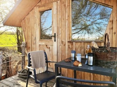 Cabane en bois avec terrasse, vue sur la nature et petit-déjeuner gourmand.