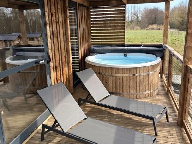 Hébergement insolite en Auvergne-Rhône-Alpes avec jacuzzi et chaises longues en bois.