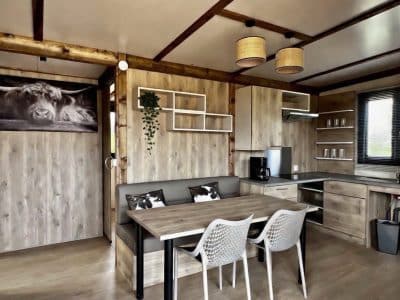 Hébergement insolite en Auvergne-Rhône-Alpes, intérieur moderne avec cuisine et table en bois.