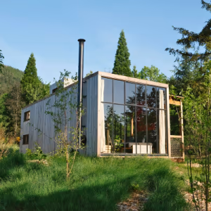 Cabane moderne en bois avec grandes baies vitrées, entourée de verdure à Champagne-Ardennes.