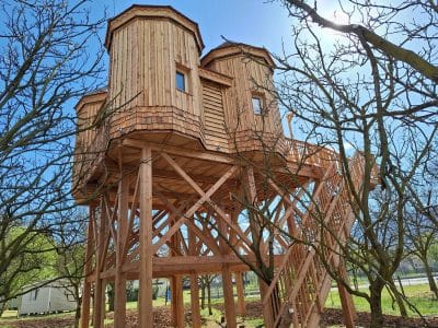 Cabane perchée en bois, sur pilotis, entourée darbres, au cœur de lAuvergne.