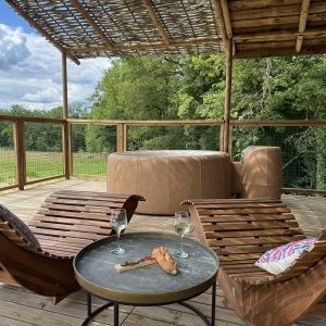 Hébergement insolite en bois avec jacuzzi, chaises longues et vue sur la nature.