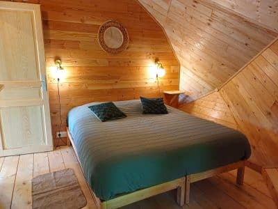 Chalet en bois en Auvergne, avec un lit douillet et des murs en bois chaleureux.