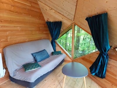 Cabane en bois avec grandes fenêtres, offrant une vue sur la nature verdoyante.