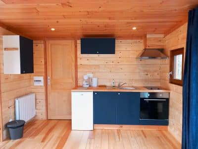 Cabane en bois moderne en Auvergne avec cuisine équipée et ambiance chaleureuse.