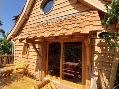 Cabane en bois avec terrasse ensoleillée, située en Auvergne-Rhône-Alpes.