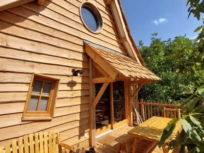 Cabane en bois avec terrasse ensoleillée et vue sur la nature en Auvergne-Rhône-Alpes.