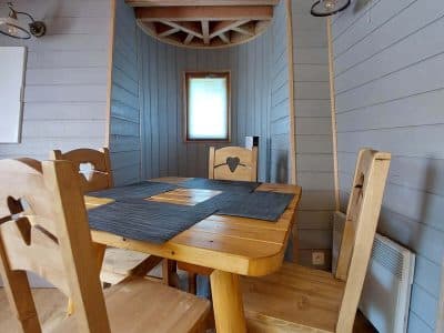 Hébergement insolite en Auvergne-Rhône-Alpes, intérieur en bois avec table et chaises chaleureuses.